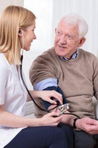 Home healthcare services nurse takes blood pressure of senior man.